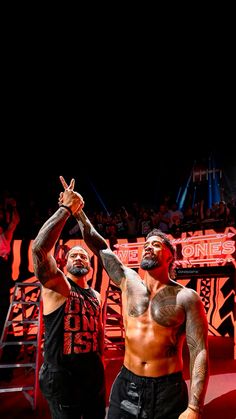 two men standing next to each other in front of a crowd at a wrestling match