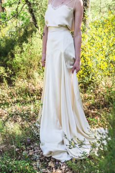 a woman standing in the woods wearing a white dress