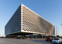 a very large building that is next to a parking lot with cars parked in front of it