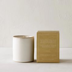 a white candle sitting next to a cardboard box