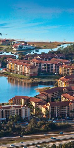 an aerial view of several buildings and water in the background with cars driving on the road