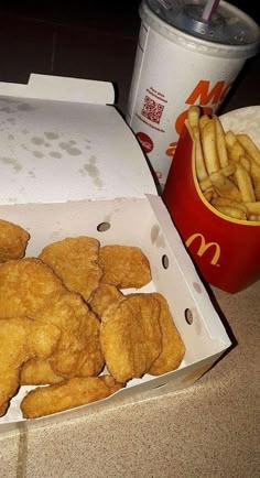 chicken nuggets and french fries in a box next to a can of mcdonald's soda