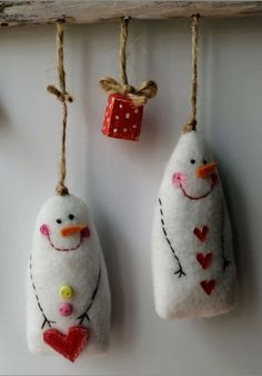 two snowmen are hanging from twine with hearts on the strings and one is holding a cup