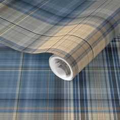 a blue and tan plaid wallpaper with a roll of tape on the floor next to it