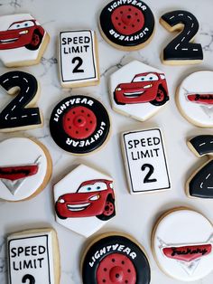 cookies decorated with cars and numbers are on a marble countertop in the shape of road signs