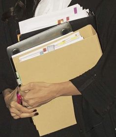 a woman is holding files and folders in her hands