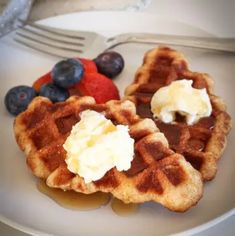 two waffles on a plate with fruit and ice cream next to a fork