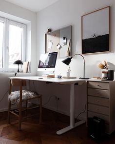 a desk with a computer on top of it in front of a window and a chair