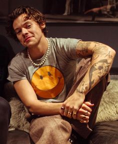 a man with tattoos sitting on a couch