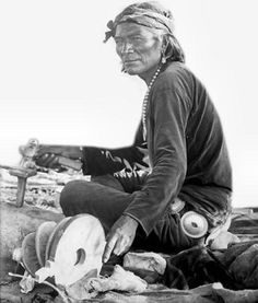 an old black and white photo of a man sitting on the ground