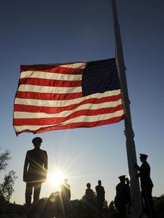 an american flag flying in the sky with silhouettes of men and women standing around it