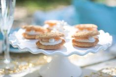 there are cookies and cream on the cake platter with champagne glasses in the background