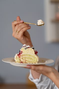 a woman holding a piece of cake on a plate with a fork in her hand