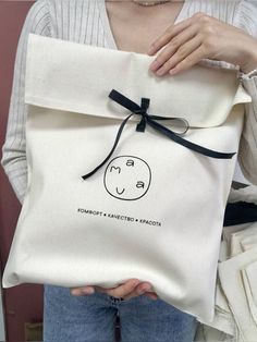 a woman is holding a bag with a smiley face on it and black ribbon around the bottom