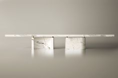 a white marble bench with two legs on the top and one leg in the middle