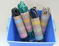 several rolls of tape are in a blue container filled with cords and paper tapes,