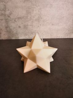 a white origami star hanging from a string on top of a black table