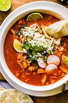 a bowl of soup with tortilla chips and limes