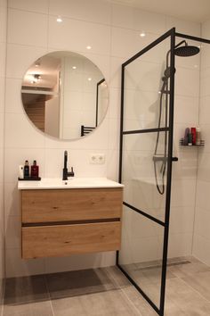 a bathroom with a sink, mirror and shower in it's center area is shown