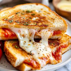 a white plate topped with two grilled cheese sandwiches next to a red pepper and tomato