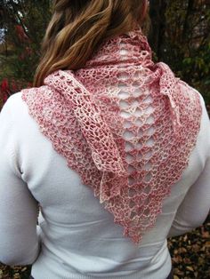 a woman wearing a pink scarf with lacy lace on the top and bottom, standing in front of some trees