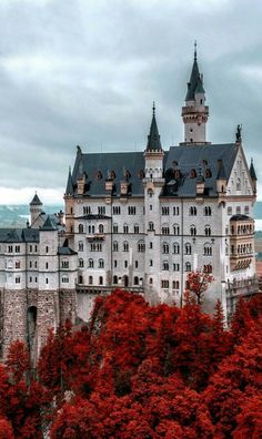 an old castle is surrounded by trees with red leaves