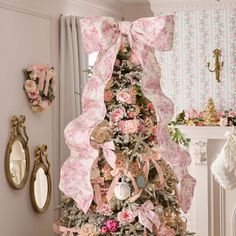 a decorated christmas tree with pink flowers and bows