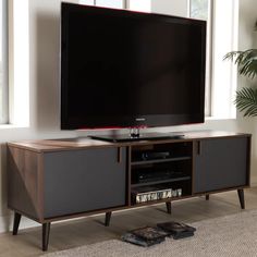 a flat screen tv sitting on top of a wooden entertainment center next to a window