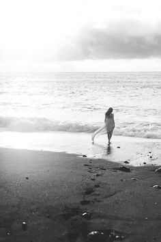 a person walking on the beach with a surfboard in their hand and footprints in the sand