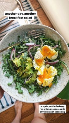 a person holding a white bowl filled with salad and an egg on top of it