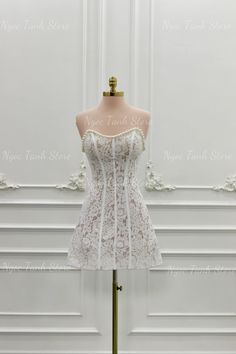 a white corset on a mannequin stand in front of a wall