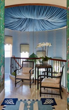 a room with blue and white wallpaper, two chairs and a table in it