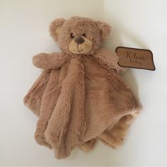 a brown teddy bear laying on top of a white wall next to a wooden sign