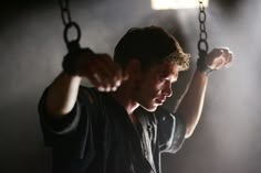 a man holding onto chains in the dark