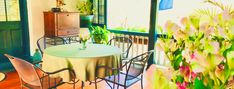 a table and chairs on a porch with flowers