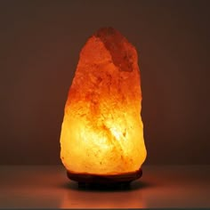 a himalayan salt lamp on a table with the light turned on and showing its bright orange glow