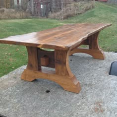 a wooden table sitting on top of a stone slab in the middle of a yard