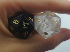 two black and gold dices sitting on top of each other in someone's hand