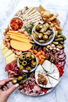 a plate full of food with olives, cheese and other foods on the side