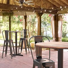 an outdoor dining area with tables and stools under a wooden pergolated roof