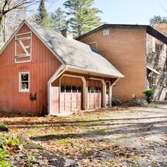 an old red barn sits in the middle of a wooded area with lots of leaves on the ground