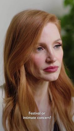 a woman with long red hair is looking at the camera