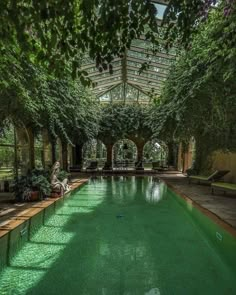 an indoor swimming pool surrounded by trees and benches