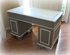 a white and gray desk sitting on top of a hard wood floor next to a door