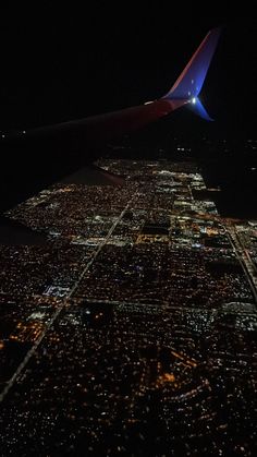 an airplane wing flying over a city at night