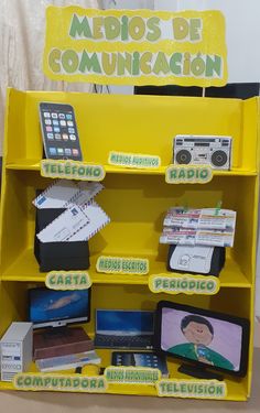 a yellow shelf filled with electronics and remotes next to a sign that says medios de comunication