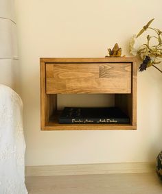 a wooden shelf with some books on it next to a flower vase and a lamp