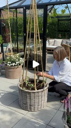 a woman kneeling down next to a potted plant