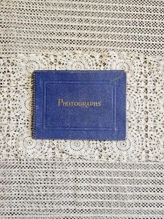 a blue book sitting on top of a white table covered in crocheted material