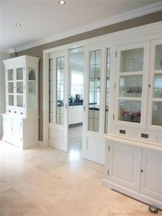 a kitchen with white cabinets and marble flooring in the middle of an empty room